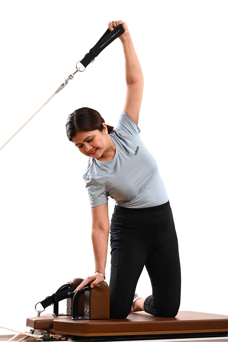 An All Core Pilates Instructor doing a Pilates pose on a Merrithew Reformer exercise machine